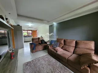 Sala de estar com sofá marrom e piso de cerâmica em um imóvel no Brasil.