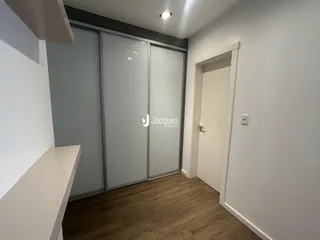 O interior da sala apresenta piso de madeira e portas de vidro modernas.