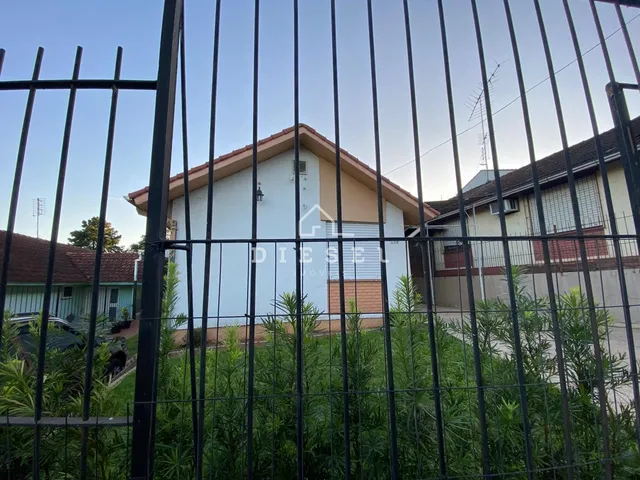Fachada de uma casa em Lajeado, Brasil, vista através de uma cerca de metal.