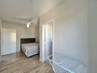 Quarto com cama e piso de madeira clara.