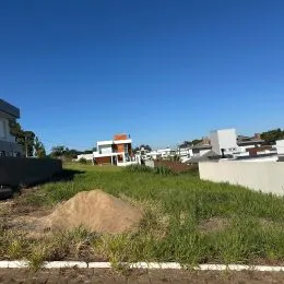 Paisagem de terra e grama seca sob um céu azul claro.