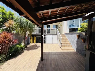 Vista externa de uma área coberta com piso de madeira e jardim em Lajeado.