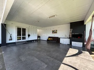 Espaço interno amplo com piso de cerâmica e lareira em uma residência.