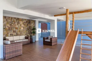 Sala de estar com sofá de vime e parede de pedra na residência.