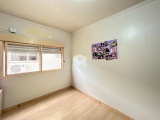 Ambiente interno de uma sala com piso de madeira e janela.