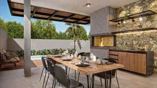 Área externa coberta com mesa de jantar de madeira e parede de pedra em Lajeado.