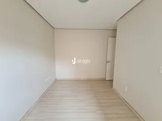 Ambiente interno com piso de madeira clara e paredes brancas.
