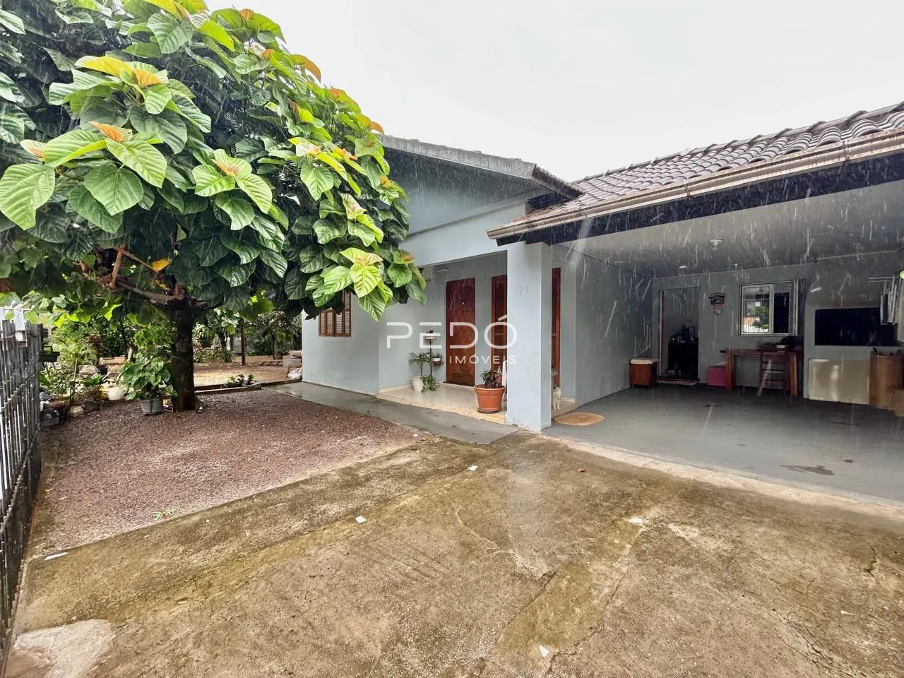 Fachada de uma casa em Lajeado, Brasil, com jardim e árvore na frente.