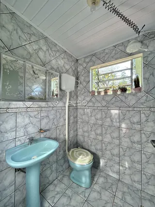 Banheiro com azulejos cinza e louças azuis.