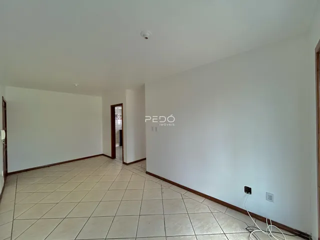 Um corredor interno com piso de cerâmica e paredes brancas.