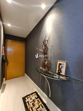Hall de entrada com porta de madeira e piso claro.