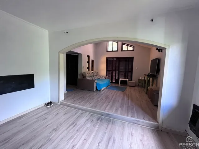 Ambiente interno com piso de madeira clara e passagem para outra área.