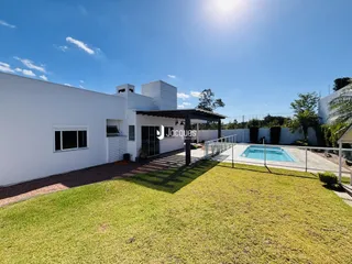 Fachada de uma residência branca com piscina e jardim em Lajeado.
