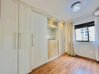 Quarto com armários embutidos e piso de madeira clara.