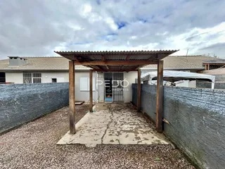 Vista externa de uma propriedade com uma estrutura de madeira e muro de vedação.