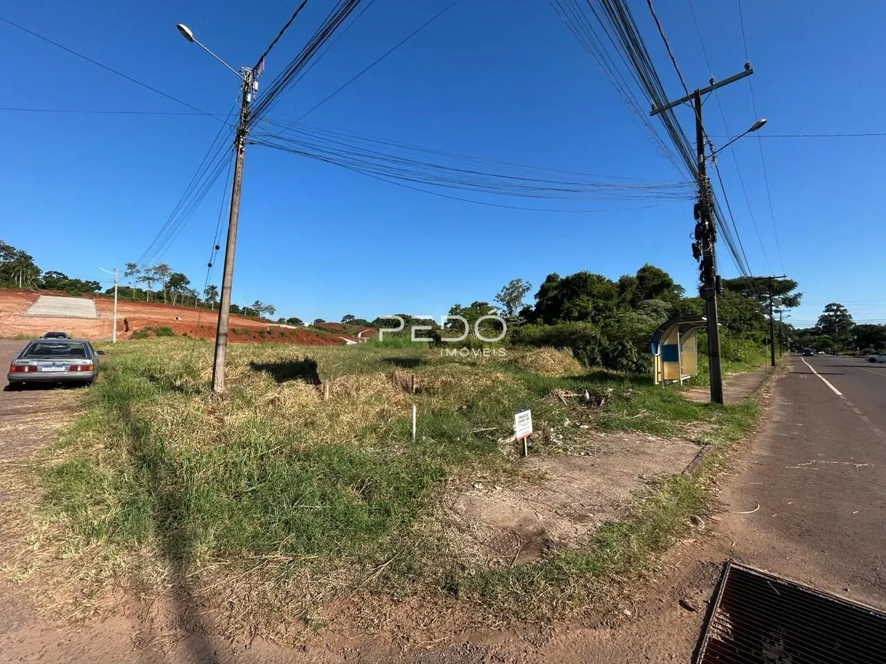 Paisagem de terra e vegetação ao lado de uma estrada.