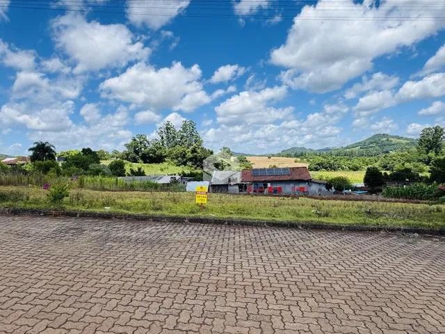 Vista externa de uma propriedade rural com vegetação e colinas ao fundo.