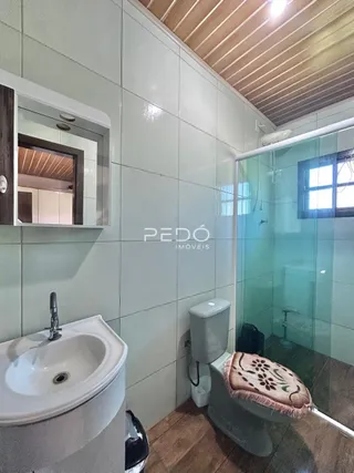 Foto de um banheiro com revestimento cerâmico e box de vidro.