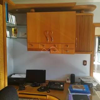 Armários de madeira e uma mesa de escritório são visíveis no ambiente interno.