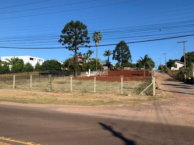 Vista externa de uma propriedade com cerca e vegetação ao longo de uma estrada.