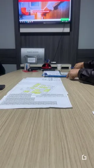 Foto de documentos e plantas sobre uma mesa em um ambiente interno.
