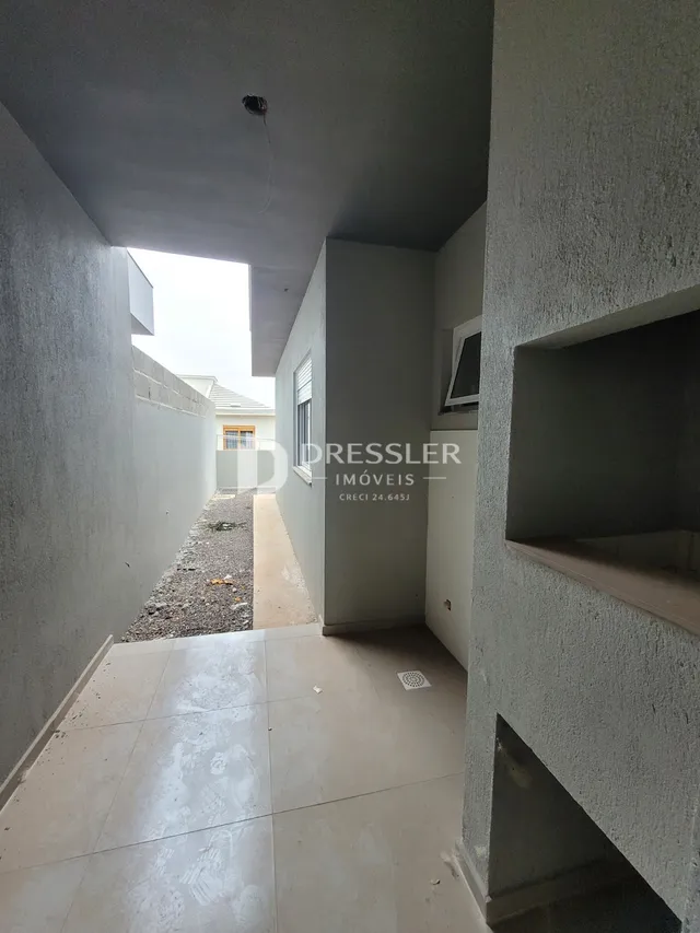 Corredor interno de uma residência com paredes brancas e piso claro.