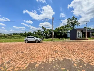 Vista externa de uma propriedade com paisagem verde e pavimento de tijolos.