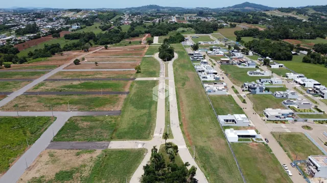 Vista aérea de uma área de terreno com campos e algumas construções no horizonte.