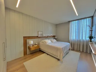 Quarto com cama e janela em ambiente claro.
