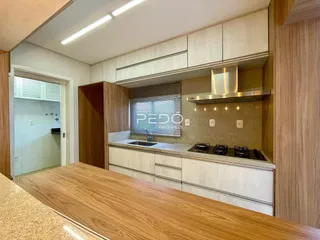 Vista da cozinha com armários de madeira e bancadas claras.