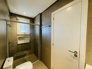 Foto de um banheiro com box de vidro e vaso sanitário.