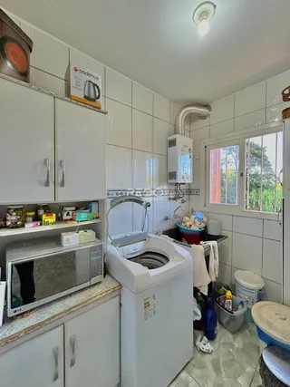 Foto da cozinha com armários brancos e piso claro.