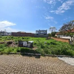 Vista externa de um terreno com piso de pavers e vegetação rasteira.