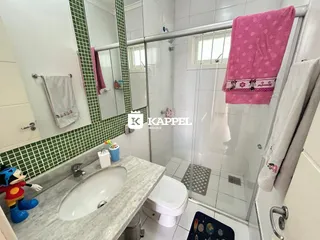 Banheiro com revestimento de azulejos verdes e bancada de mármore.