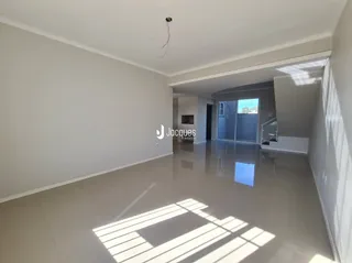 Interior de uma sala com piso claro e paredes brancas.
