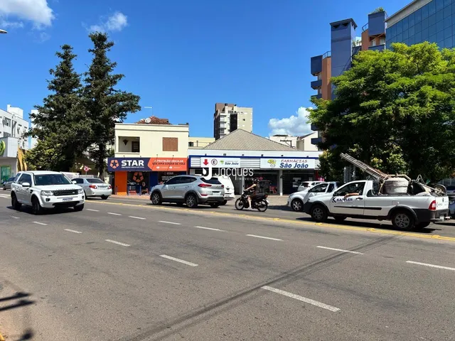 Vista da rua em Lajeado, Brasil, com veículos estacionados e edifícios ao fundo.