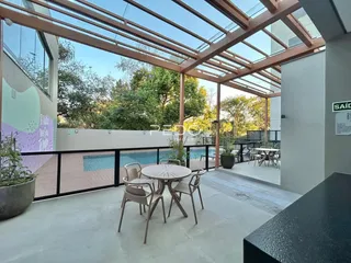 Área externa com pérgula e vista para uma piscina no imóvel.