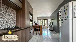 Imagem interna de uma cozinha com armários de madeira e revestimento de azulejos.