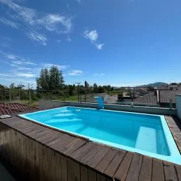 Foto da piscina externa com deck de madeira em uma propriedade.
