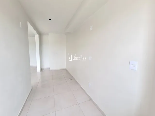 Corredor interno de um apartamento moderno com piso claro e paredes brancas.