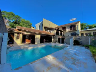 Foto de uma piscina externa adjacente a uma residência com telhado de telha.