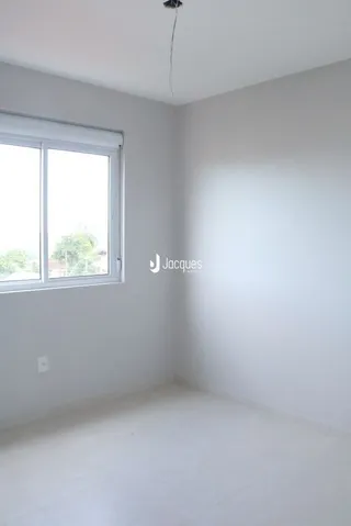 Ambiente interno de uma sala com paredes brancas e uma janela.