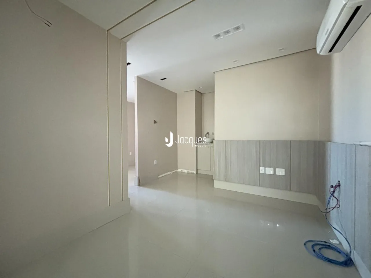 Hall da casa com piso claro e paredes brancas.
