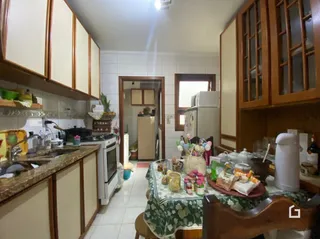 Foto interna de uma cozinha com armários de madeira e piso cerâmico.