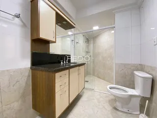Foto de um banheiro com armários de madeira e piso de cerâmica.