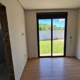 Ambiente interno com piso de madeira e porta de vidro que dá para o exterior.