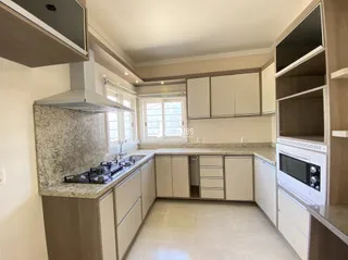 Vista interna de uma cozinha com armários e bancadas claras.