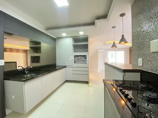 Vista da cozinha moderna com armários brancos e bancadas escuras.