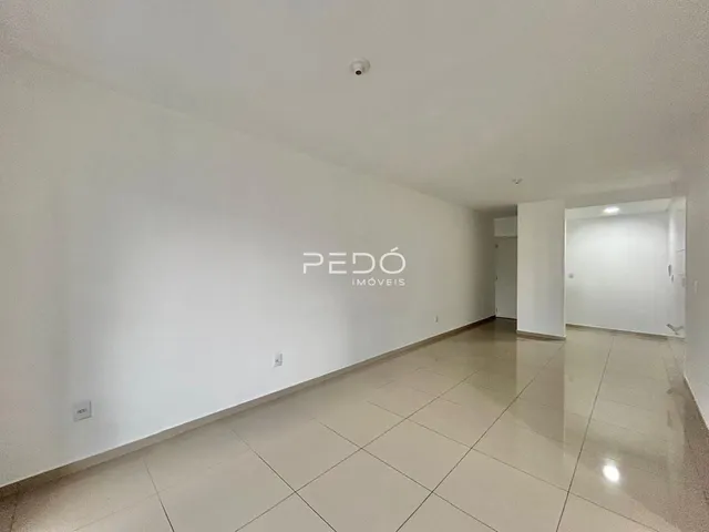 Vista de um corredor interno com paredes brancas e piso de cerâmica.