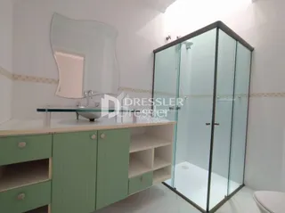 Foto de um banheiro com armário verde e box de vidro.